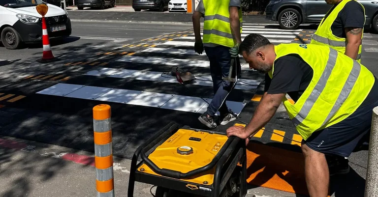 Montaj de limitatoare de viteza din cauciuc la o trecere de pietoni, de catre muncitori in veste reflectorizante